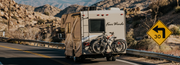 RV with bicycles on a desert road with a  speed limit sign.
